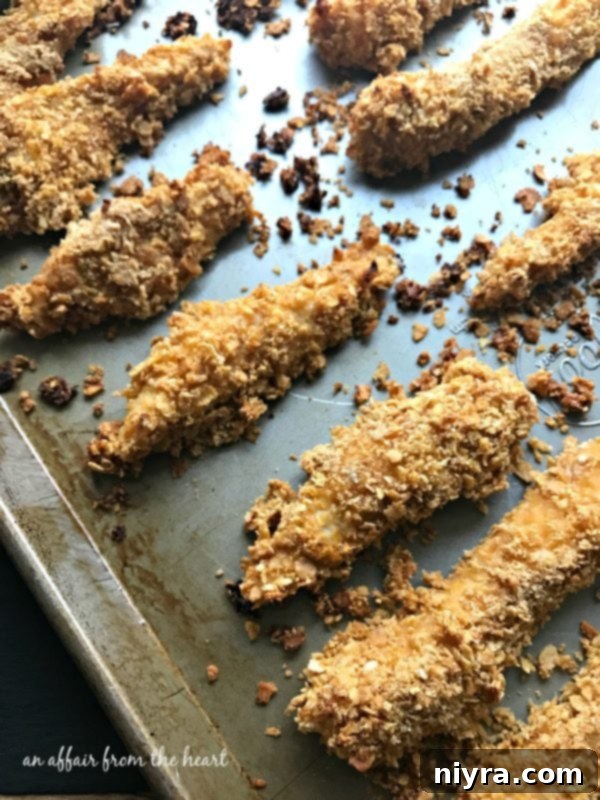 Baked chicken tenders arranged on a baking sheet, ready for the oven