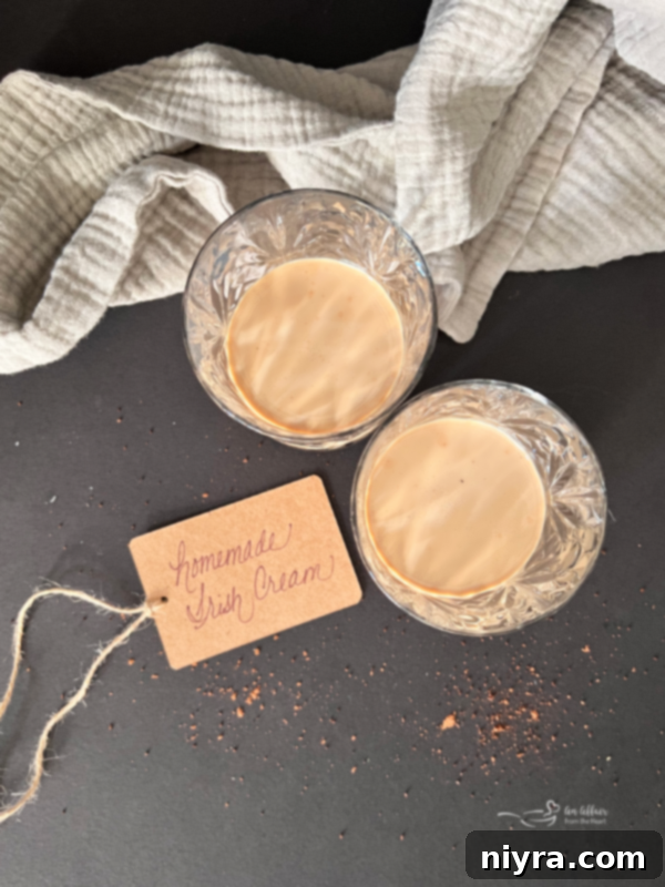 Velvet Irish Liqueur from Scratch 7 Homemade Irish cream served in a clear glass with a generous amount of ice, garnished attractively, ready for enjoyment.