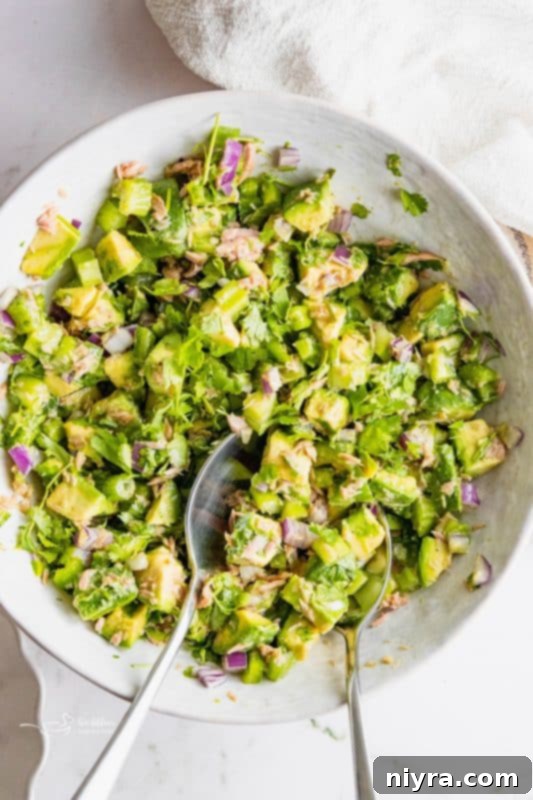 A close-up shot of the creamy and chunky avocado tuna salad in a white bowl.