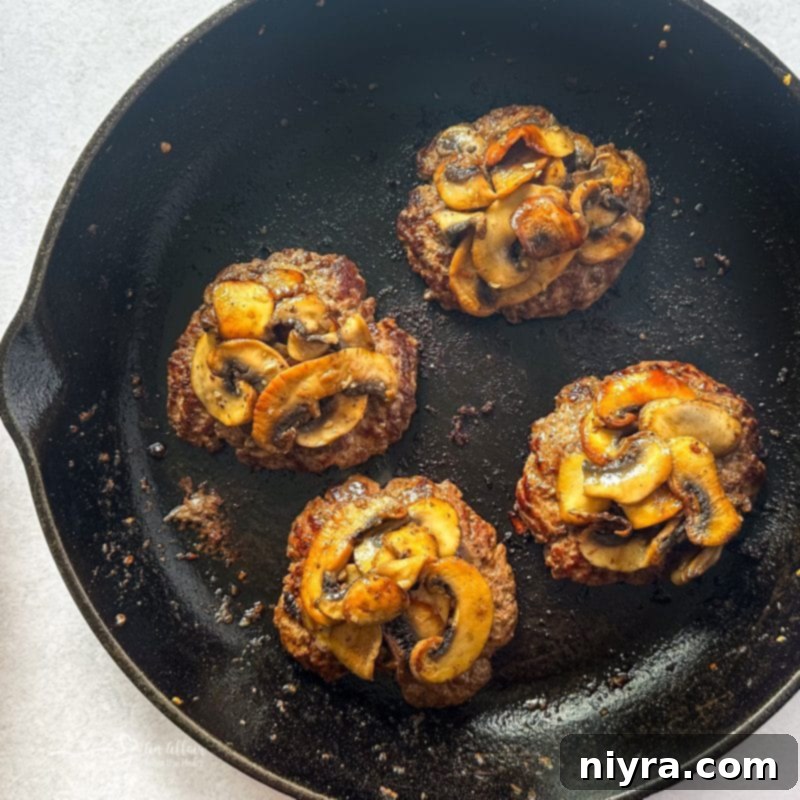 Close-up of a sizzling Mushroom Swiss Burger with melted cheese and mushrooms.