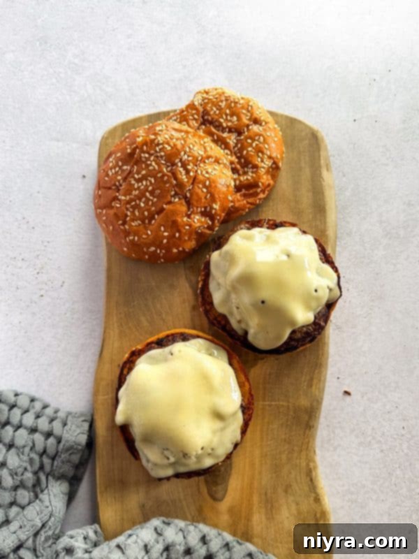 A cooked burger patty topped with melted Swiss cheese and sautéed mushrooms.
