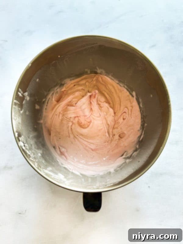 Melted chocolate being spread over the baked shortbread crust in a springform pan