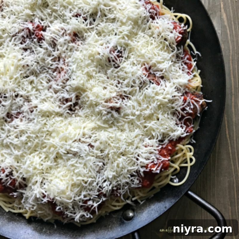 Cheese layered on top of spaghetti and meatballs