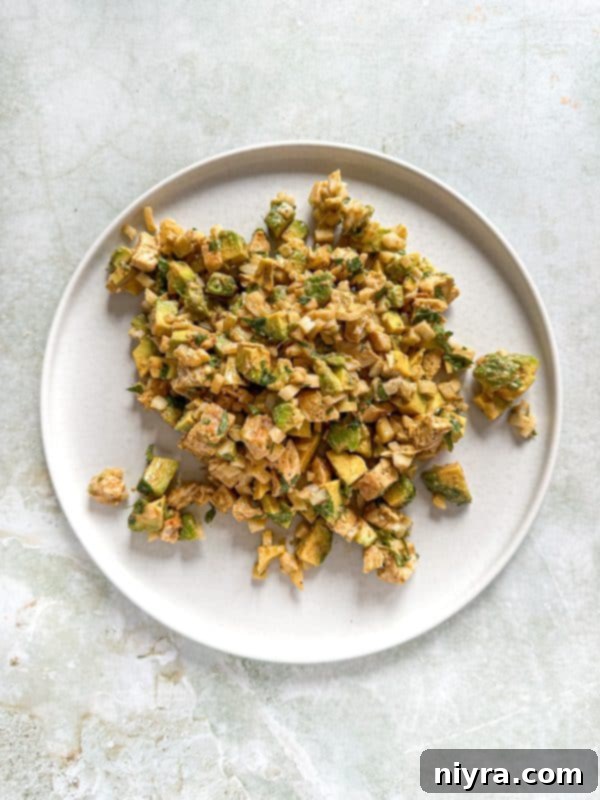 Close-up of a serving of Avocado Chicken Salad Dip with crackers on a plate.