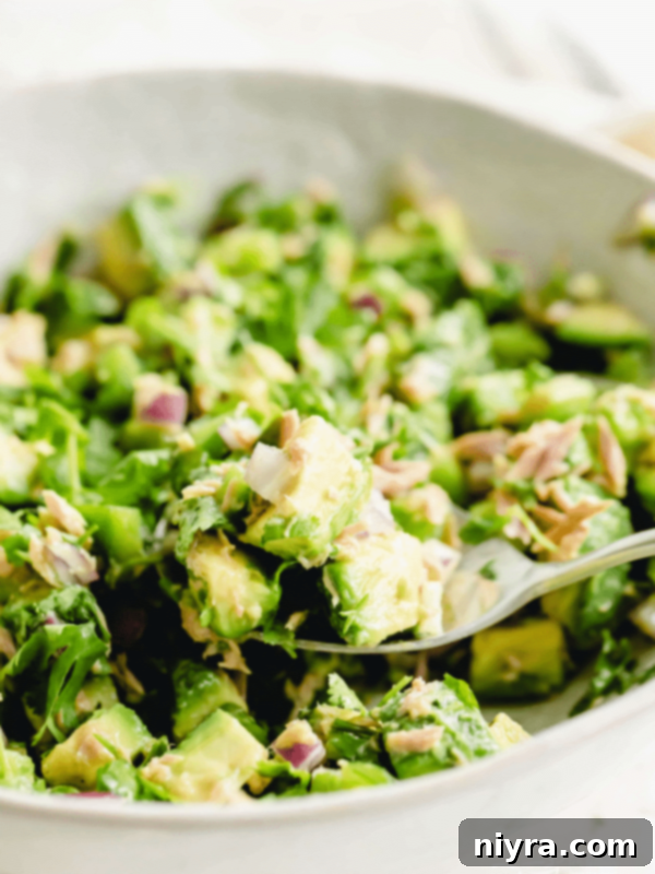 AVOCADO TUNA SALAD STORY Poster Image - a bowl of avocado tuna salad with crackers and herbs.