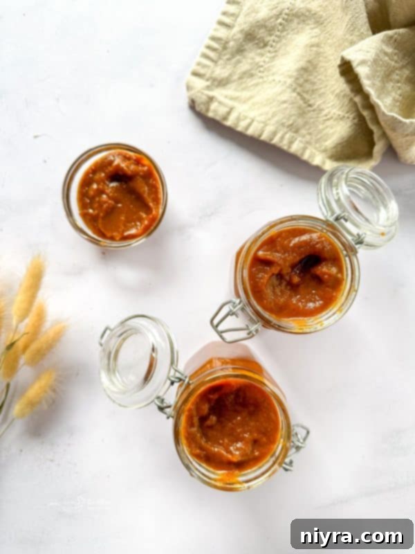 A mason jar filled with pumpkin butter and a spoon, ready to be enjoyed.