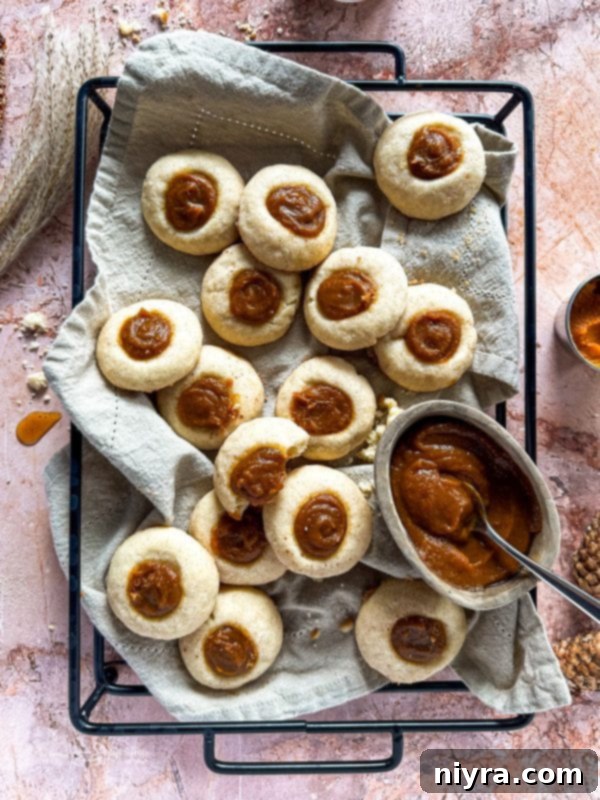 Snickerdoodle Thumbprint Cookies with a pumpkin butter filling, arranged on a rustic tray.