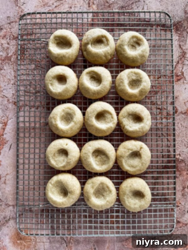 Snickerdoodle Thumbprint Cookies baked and cooled on a wire rack, ready for filling.