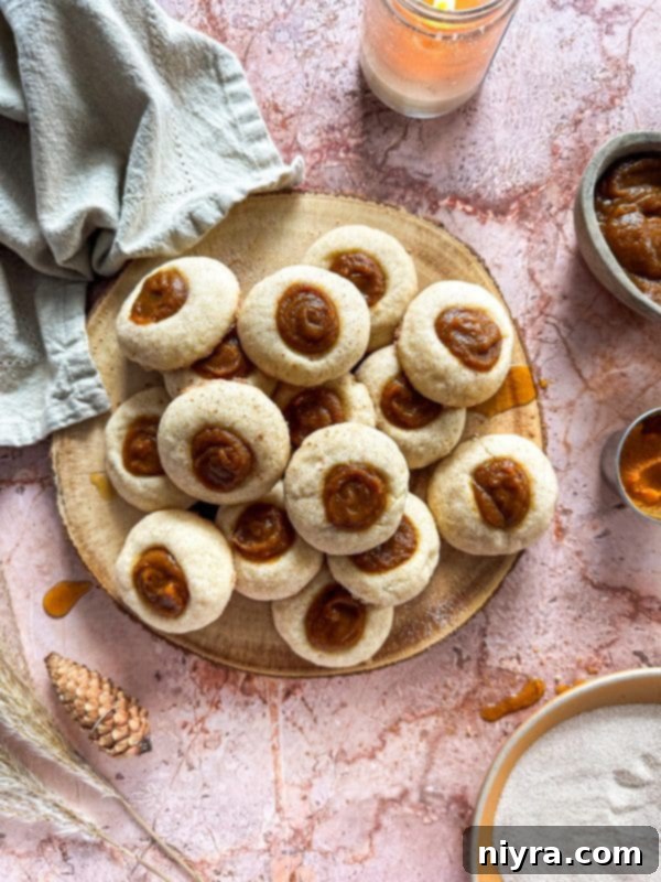 Three Snickerdoodle Thumbprint Cookies with pumpkin butter filling on a baking sheet, ready to be served.