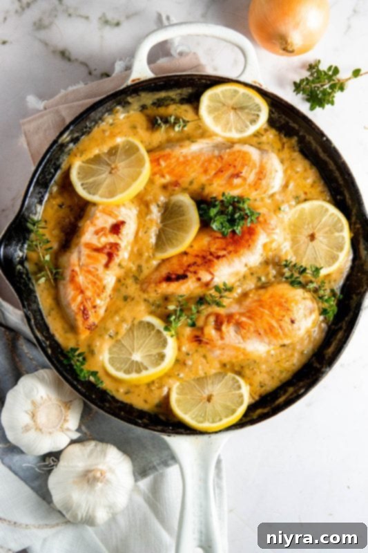 Lemon chicken in a skillet, garnished with fresh herbs.