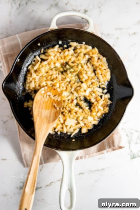 Diced onions and minced garlic sauteing in a skillet with butter.