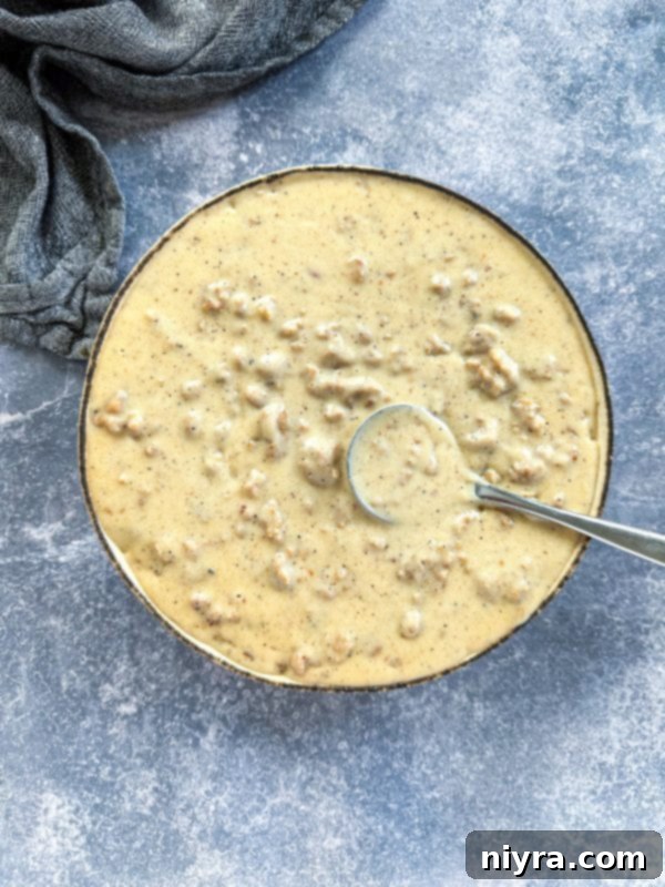 A close-up view of sausage gravy in a large skillet, highlighting its creamy texture.