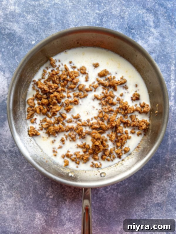 Flour sprinkled over browned sausage in a skillet, beginning the roux for the gravy.