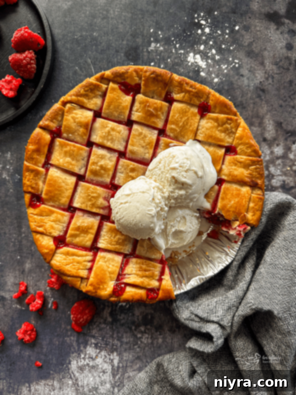 A slice of raspberry pie served with ice cream