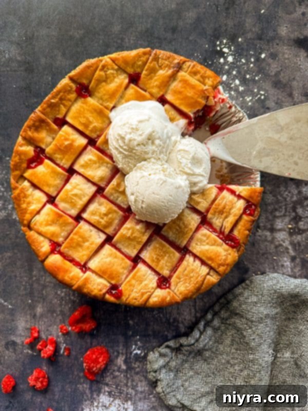 A stunning close-up of a homemade fresh raspberry pie, showcasing the vibrant red filling through a perfectly golden, flaky lattice crust