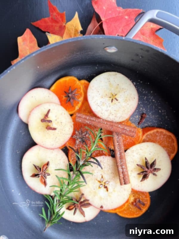 Sliced apples and oranges being placed into a pot for an autumn simmer pot.