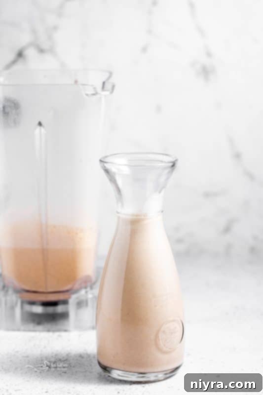 Homemade Blender Eggnog 5 A close-up of a glass of frothy homemade eggnog, garnished with a sprinkle of nutmeg.