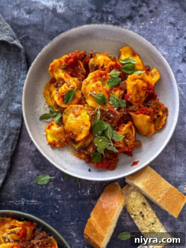 A large serving of slow cooker ravioli lasagna on a white plate, showing melted cheese and rich sauce.