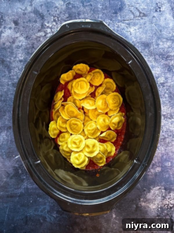 Step 3: Spreading half of the spaghetti sauce in the bottom of the slow cooker.