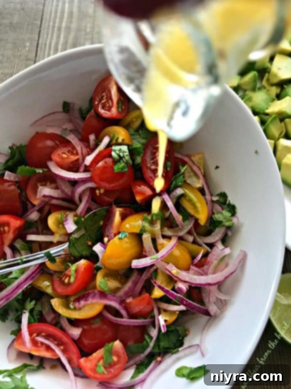 Layered Guacamole Salad 10 Tomatoes, red onion, and cilantro being tossed with the lime dressing in a bowl