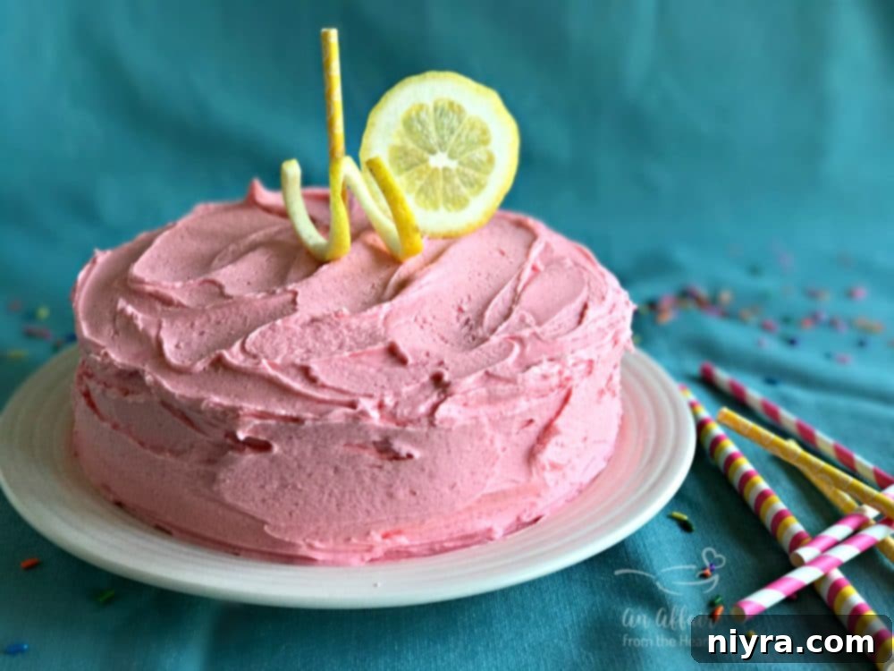Beautiful slice of Pink Lemonade Cake on a white plate with a fork, ready to be enjoyed.