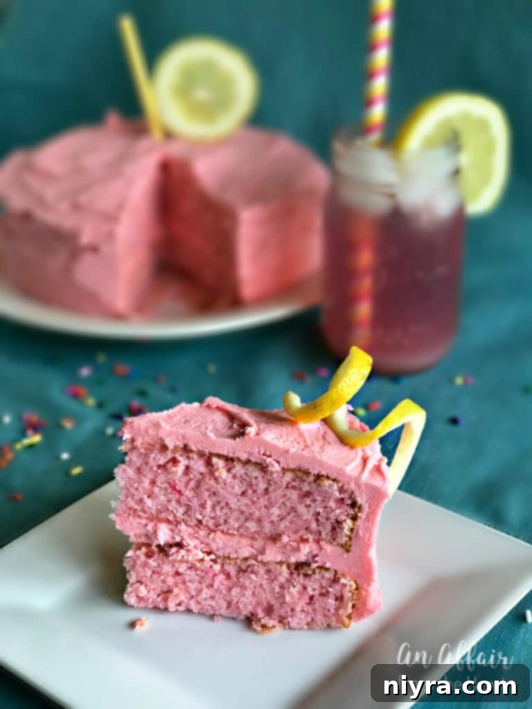 A vibrant Pink Lemonade Cake presented on a stylish cake stand, garnished with fresh lemon slices and zest, awaiting guests.