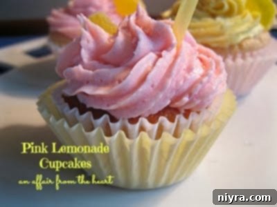 Pink Lemonade Cupcakes with swirls of pink frosting and colorful sprinkles, beautifully arranged on a white background.