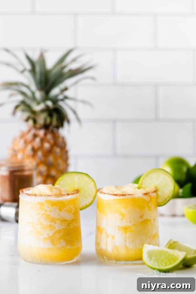 A vibrant Frozen Pineapple Margarita in a classic stemmed glass, garnished with a lime wedge, highlighting its refreshing quality.