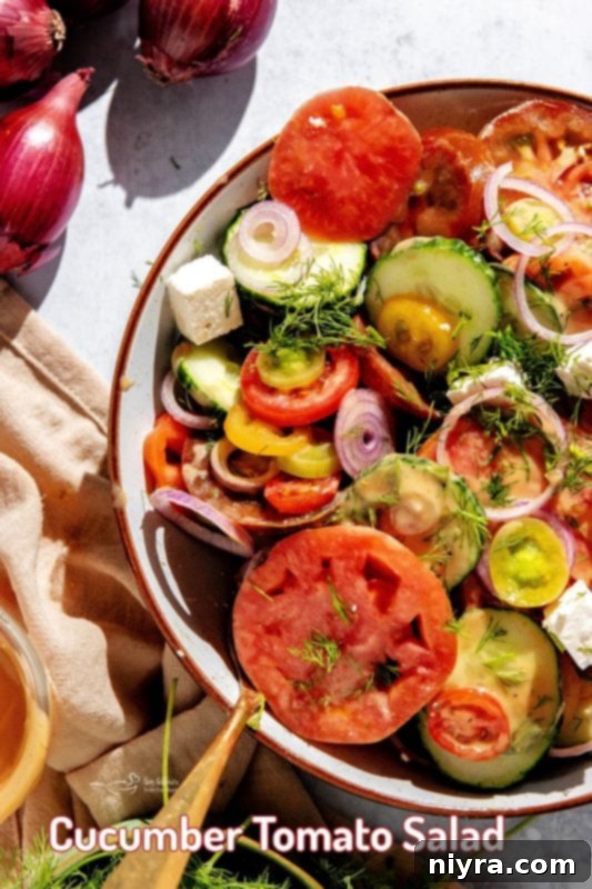 A beautifully arranged serving of cucumber tomato salad on a table with other dishes.