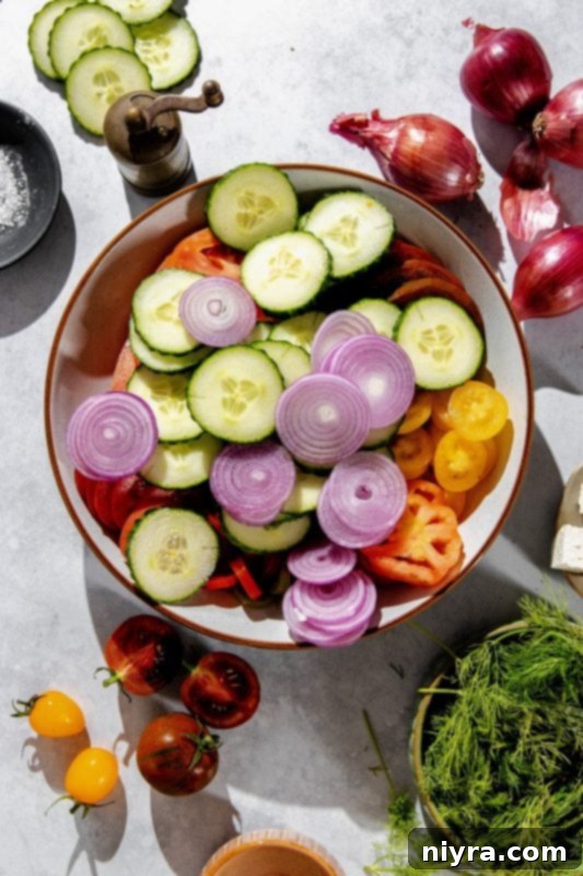 Step 2: Tossing tomatoes, cucumber, and red onions in a large bowl.