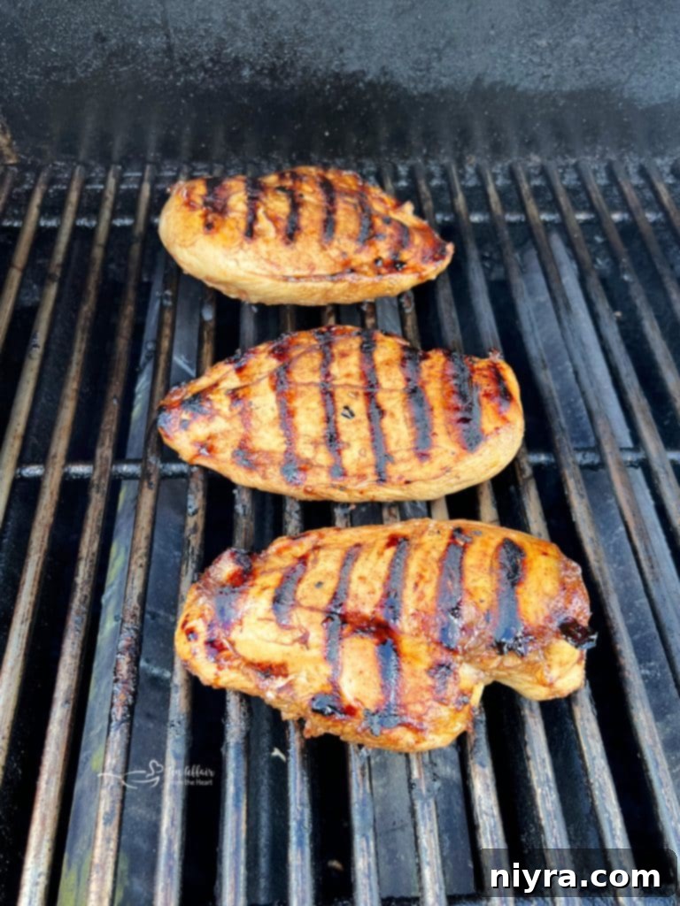 Chicken breasts cooking on a hot grill, showing early grill marks.