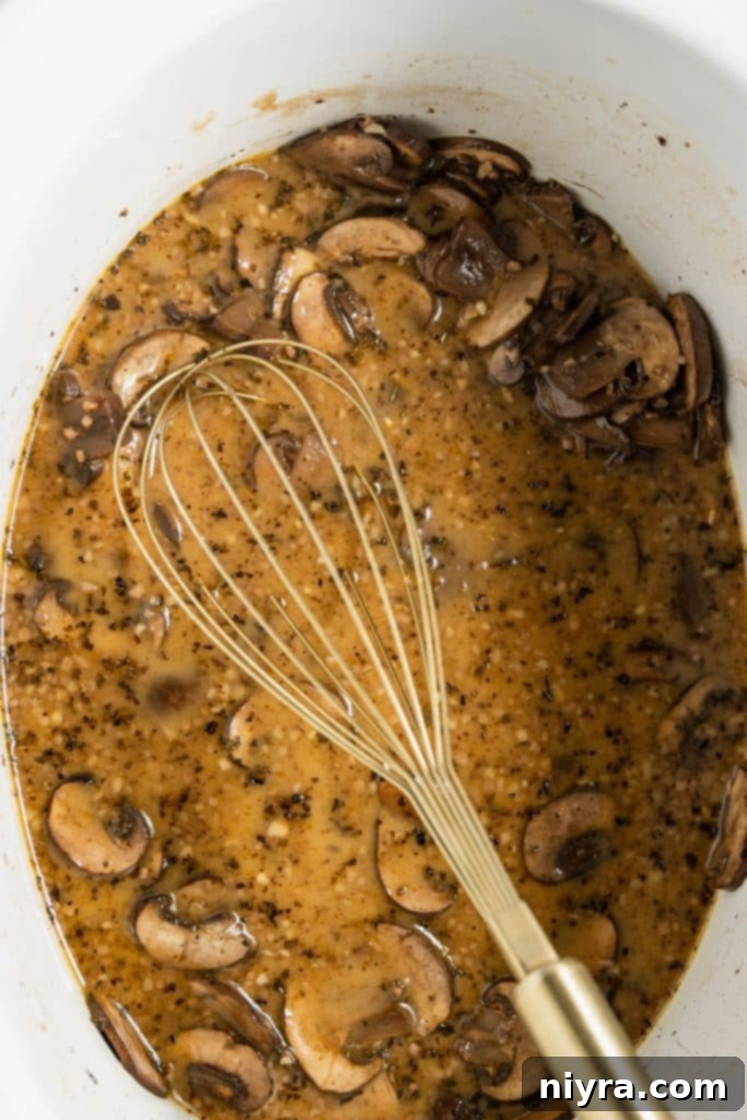 Easy Slow Cooker Chicken Marsala 11 Cornstarch slurry and heavy cream added to the Marsala wine mixture in the slow cooker, being whisked.