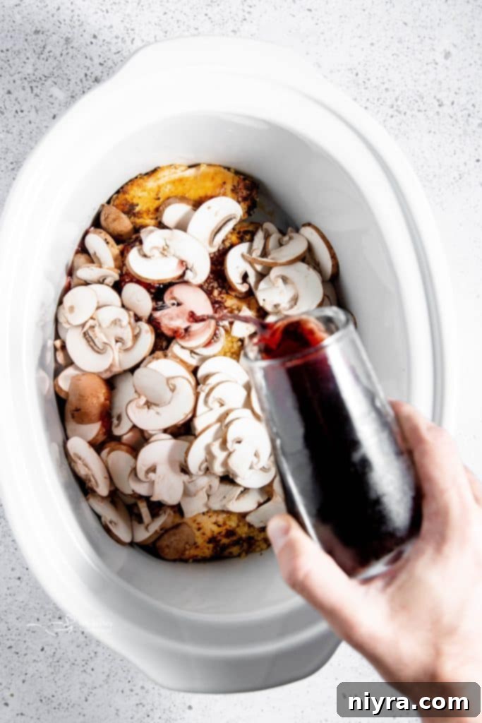Easy Slow Cooker Chicken Marsala 9 Chicken being removed from the slow cooker and placed on a plate.