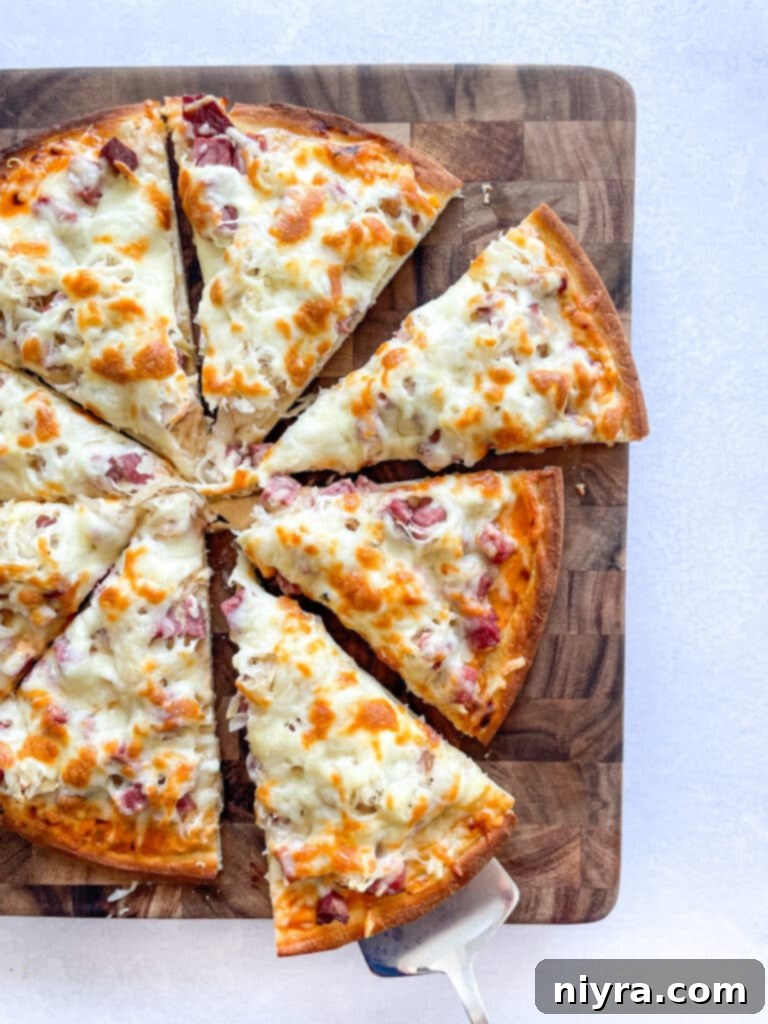 Close-up of a perfectly sliced Reuben pizza on a rustic cutting board, showcasing its unique toppings.