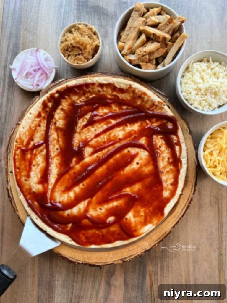 Spreading barbecue sauce evenly over the pizza crust.