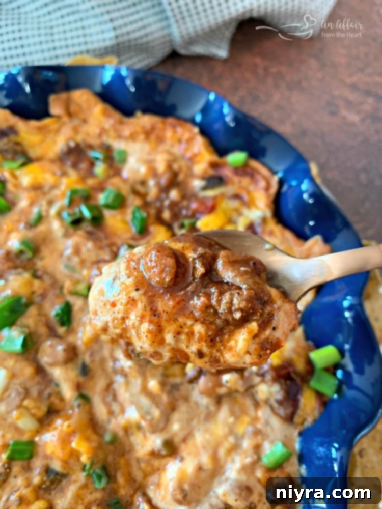 A close-up of a spoonful of warm Chili Cheese Bean Dip, rich and savory.