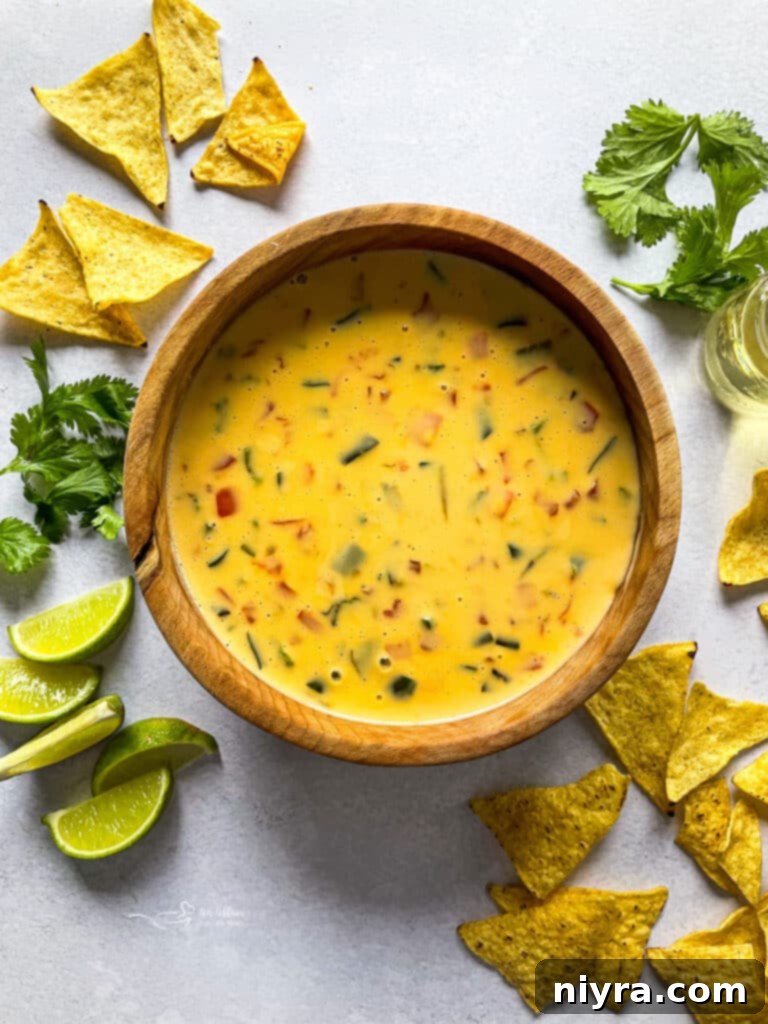 Creamy Qdoba Queso Dip, garnished with fresh lime slices and served with tortilla chips.