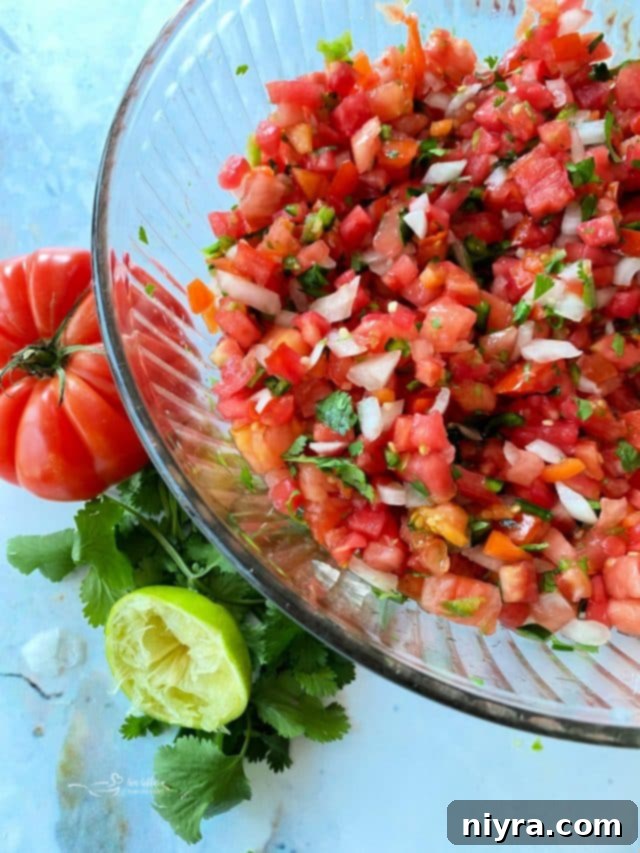 An overhead shot of fresh Pico de Gallo in a clear bowl, showing its colorful ingredients.
