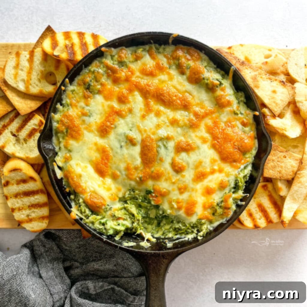 A sizzling skillet of Spinach Artichoke Dip, surrounded by perfectly grilled bread for dipping.
