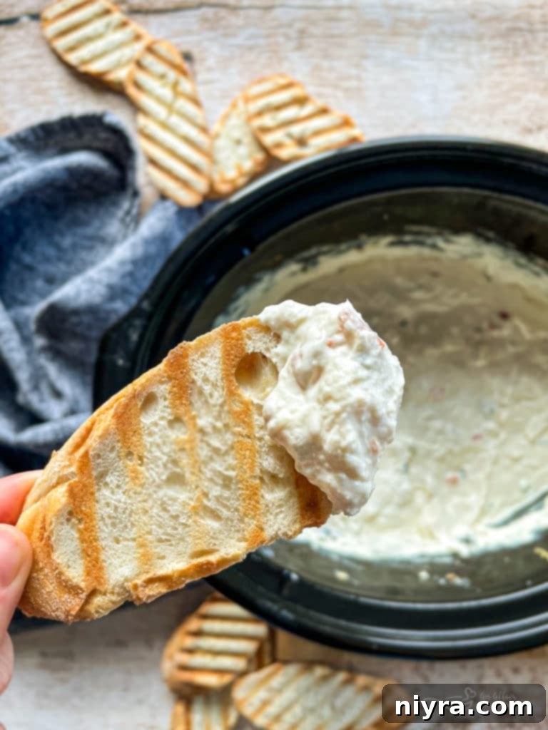 Close up of creamy Slow Cooker Crab Dip served on a piece of toasted bread.