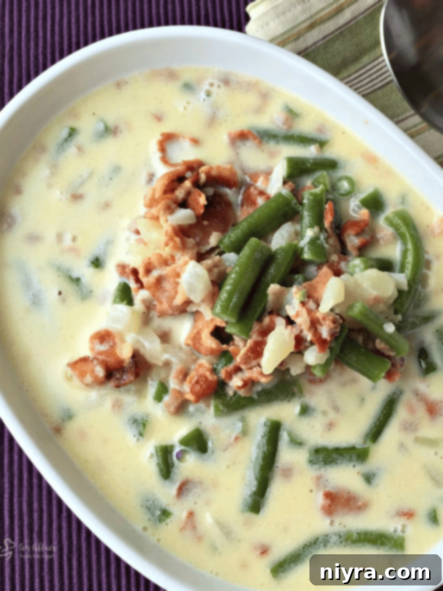Close up of Potato Green Bean Bacon soup in a white serving bowl.