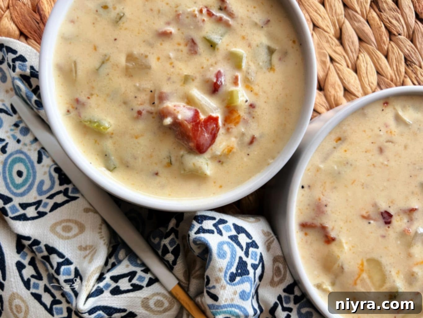 A close-up shot of creamy bacon soup in a rustic bowl with a spoon, highlighting the rich texture and bacon bits.