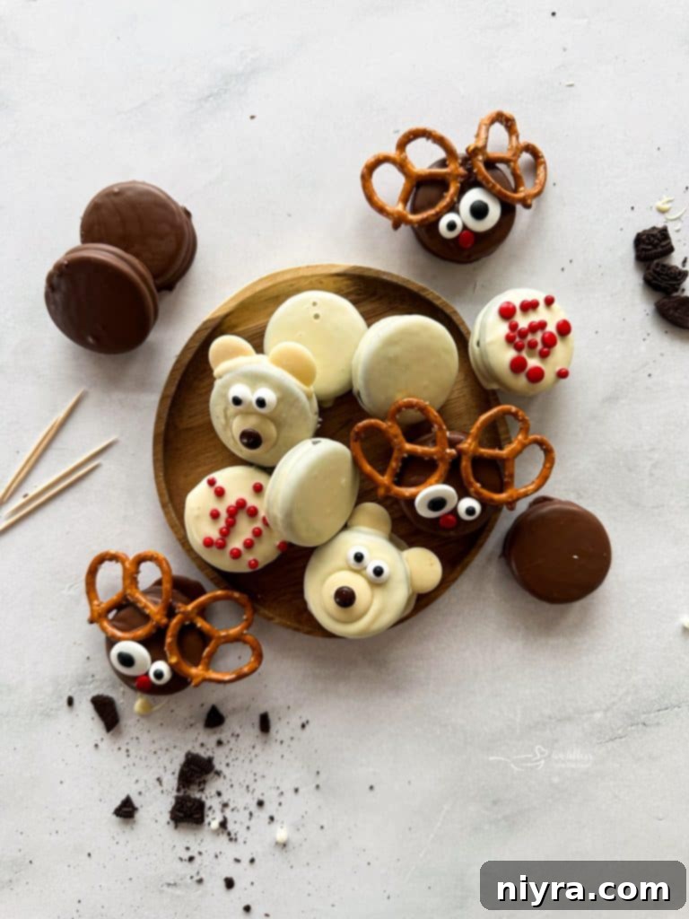 Freshly dipped Oreos on a parchment-lined baking sheet, some plain and some decorated as reindeer, with melting chocolate in the background.