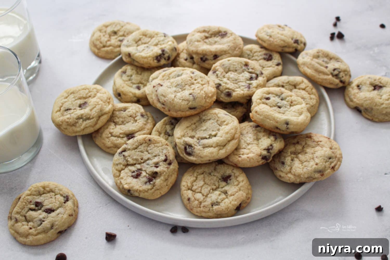 Overhead shot of two Chocolate Chip Sugar Cookies and a glass of milk, with an inviting, cozy feel.