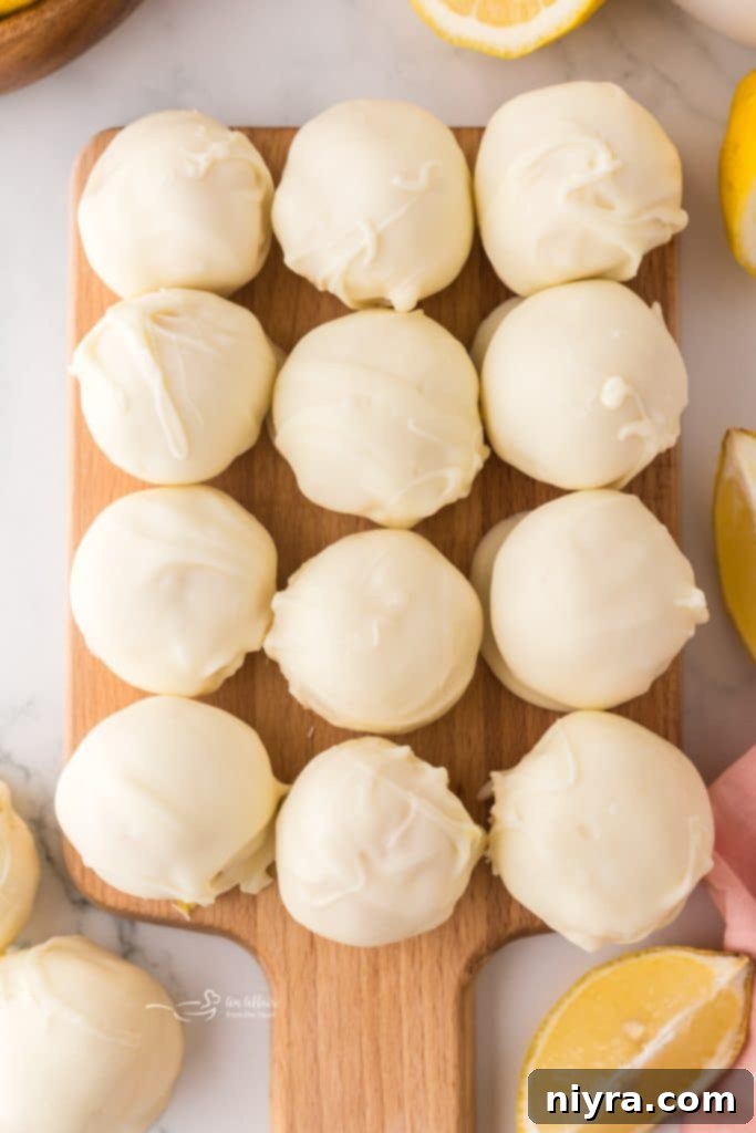 Close-up of a perfectly round, white chocolate lemon truffle, showcasing its smooth coating and bright yellow color.