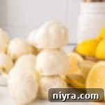 Easy Lemon Truffles stacked next to lemons in various stages of being sliced.