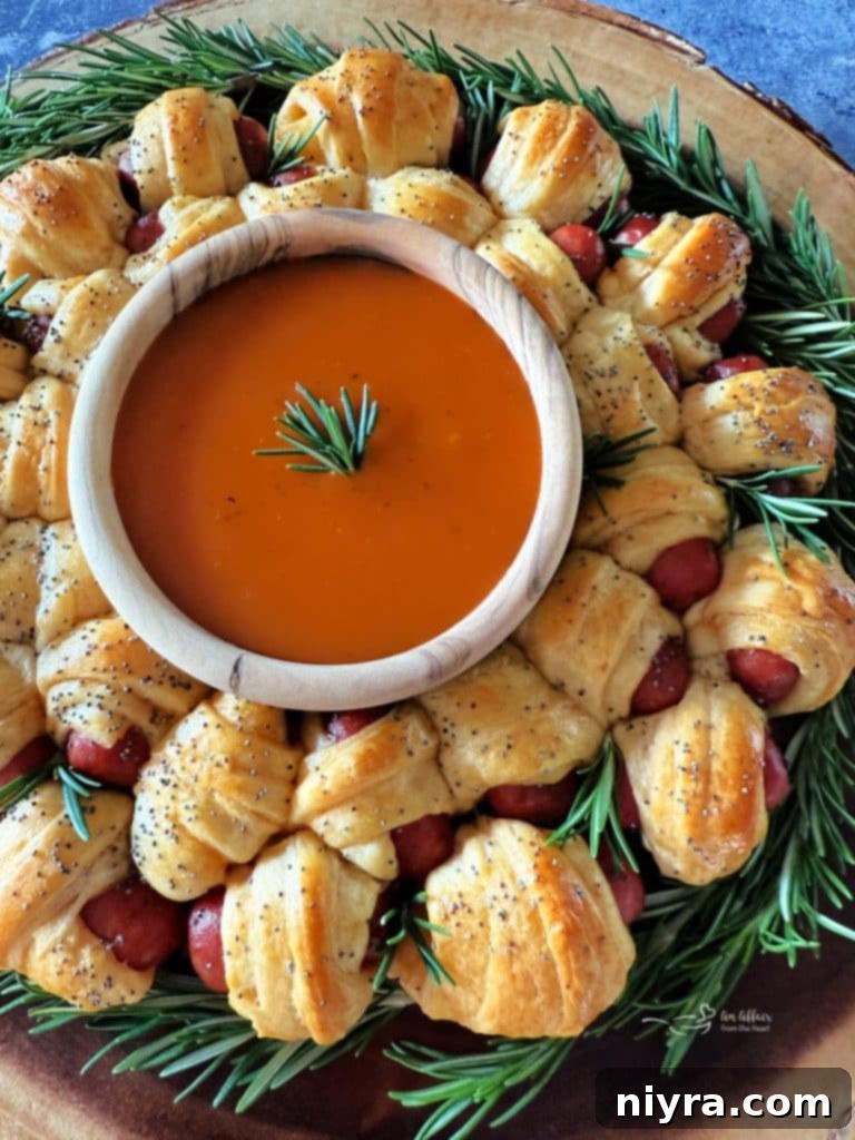Pigs in a Blanket Wreath garnished with rosemary and a dipping bowl of Dorothy Lynch, on a wooden platter.