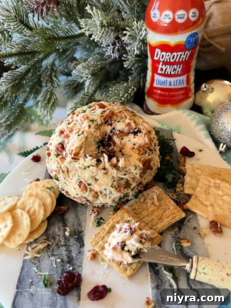 Dorothy's Holiday Cheese Ball plated with festive decorations and a bottle of Dorothy Lynch dressing in the background.