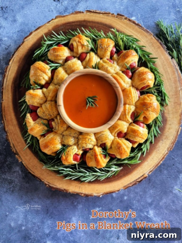 Hero shot of the Pigs in a Blanket Wreath on a wooden serving board with fresh rosemary garnish and a bowl of Dorothy Lynch.