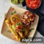 Overhead of Chicken & Cowboy Caviar Taquitos on a plate with a small bowl of Cowboy Caviar.